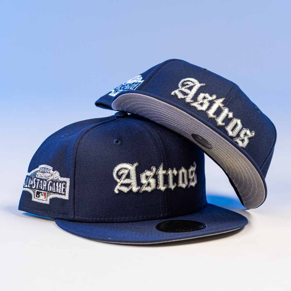 Two Fat Elvis OE ASG Dark Blue New Era Hat 5950 Fitted caps, featuring 'Astros' in white on the front and an All-Star Game patch on the side, are displayed against a light blue background.