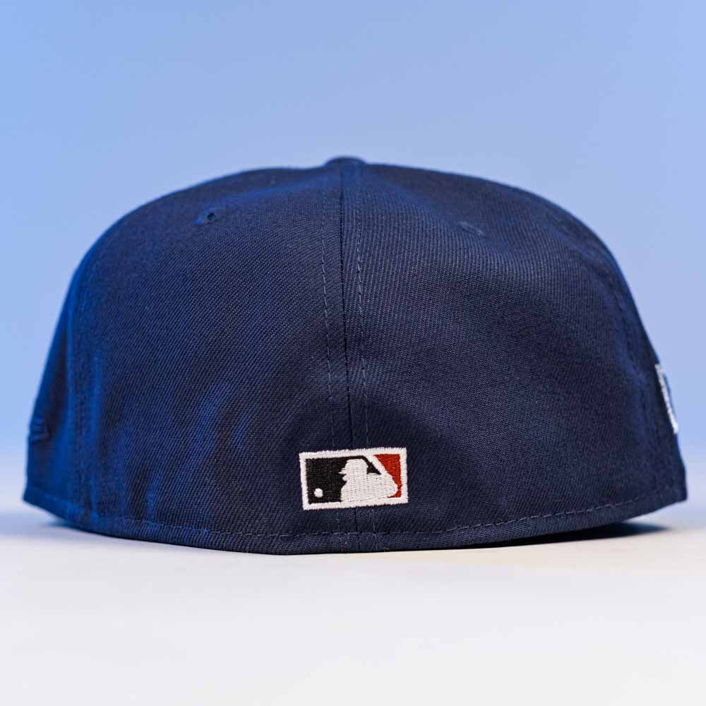 The Fat Elvis OE ASG Dark Blue New Era Hat 5950 Fitted is shown from the back, featuring the official MLB logo embroidered near the bottom edge against a light blue background.