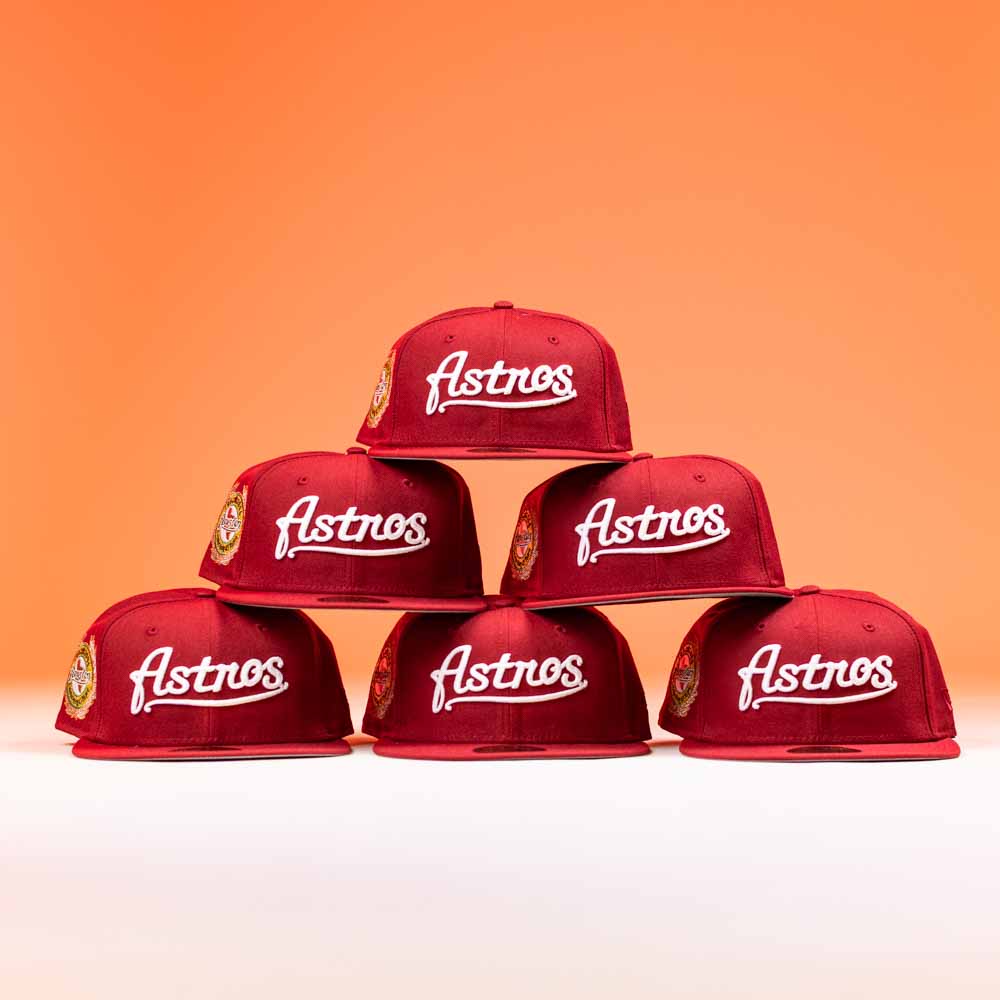 Six The Big Puma Cardinal White Script New Era Hat 5950 Fitted caps are arranged in a pyramid against an orange background. Each features “Astros” script on the front and a patch on the left side.