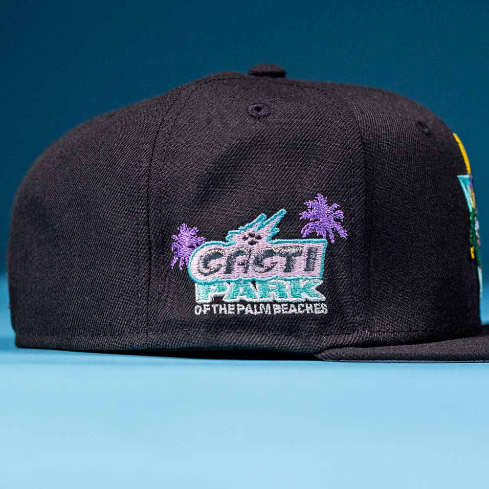 A black Flamingo and Chill Bo Bundy 2022 Houston Astros 5950 Fitted New Era Hat features embroidered purple palm trees and teal "GACHI PARK OF THE PALM BEACHES" text on the side, shown against a blue background.