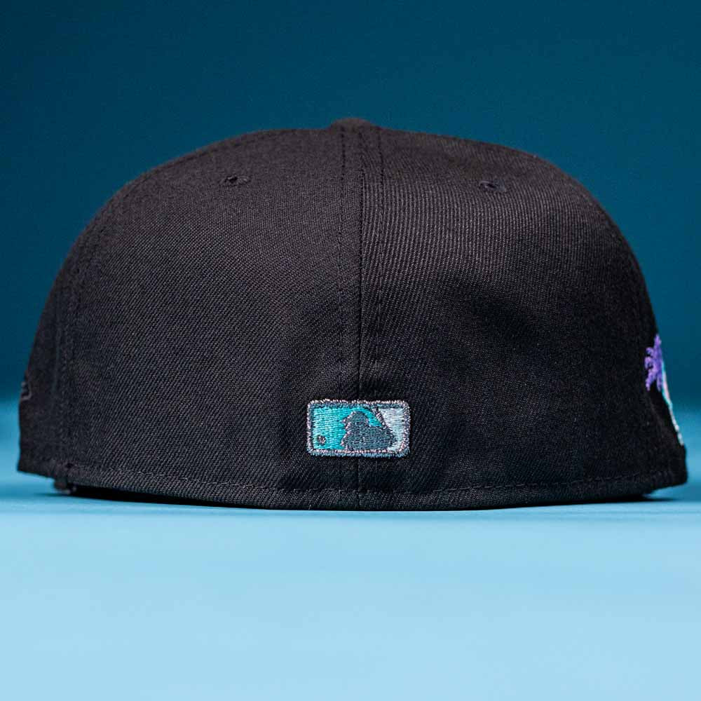 The Flamingo and Chill Bo Bundy 2022 Houston Astros New Era Hat 5950 Fitted is shown from the back, with a small, rectangular embroidered MLB logo in teal, black, and white above the brim against a blue background.