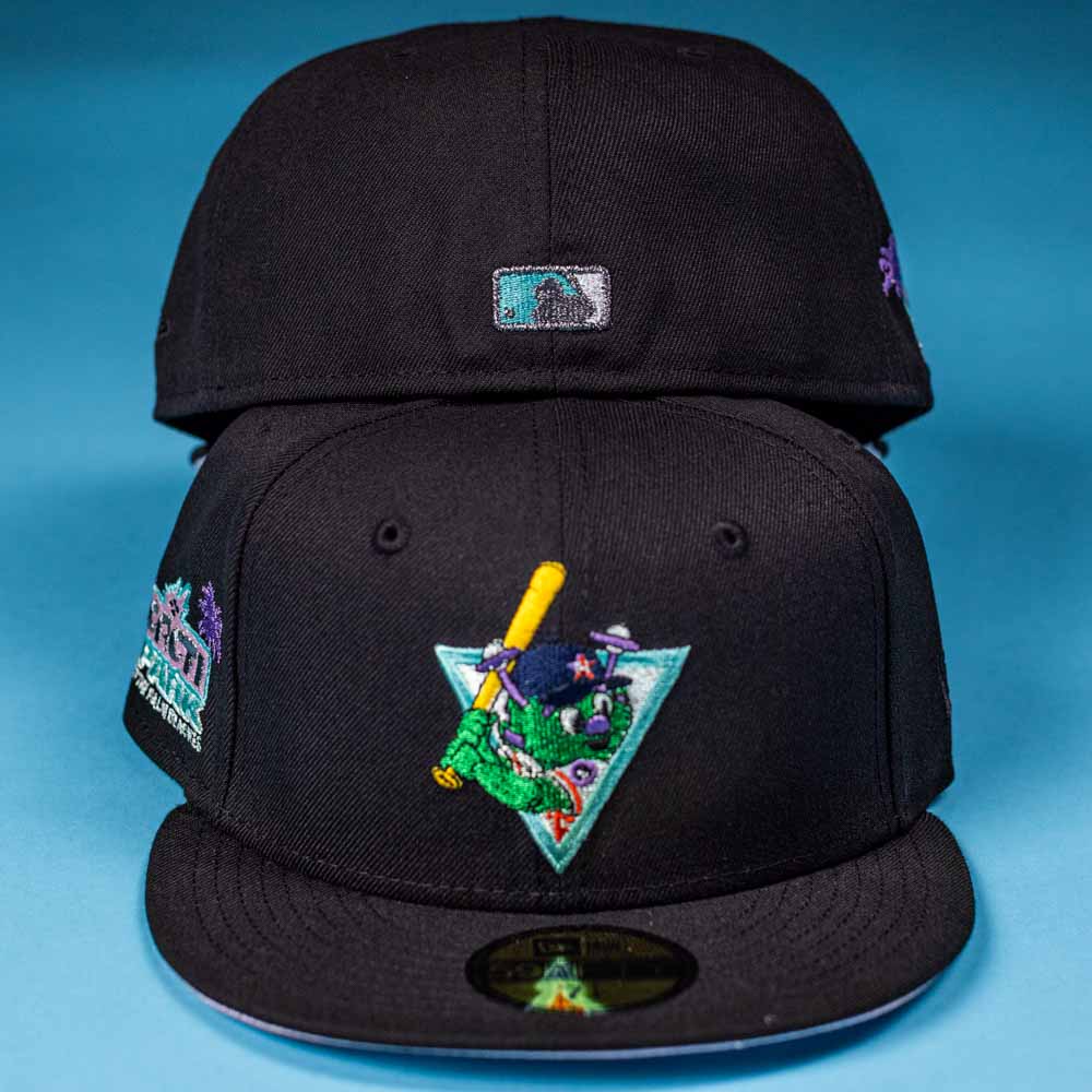 Two black Flamingo and Chill Bo Bundy 2022 Houston Astros New Era 5950 Fitted caps are on a blue background; the front cap has a colorful cartoon character with a bat and triangle, while the back shows a small rectangular patch.