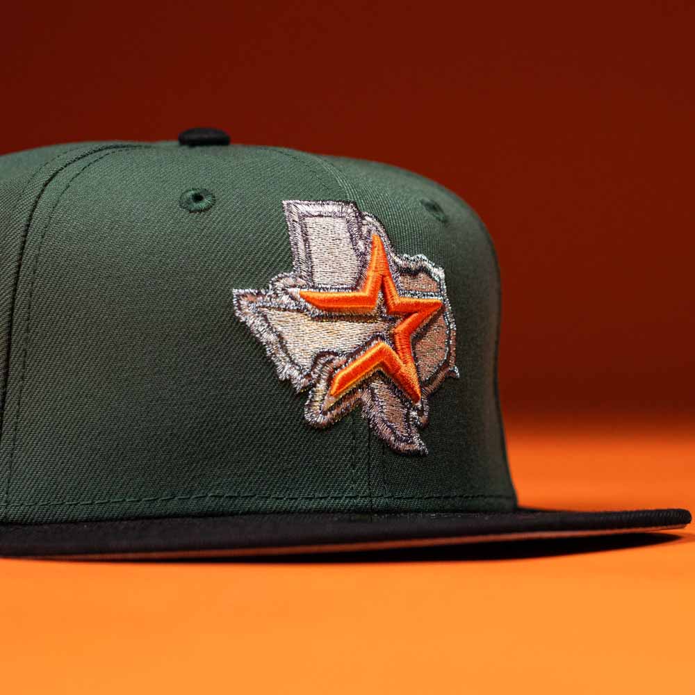 The El Jager Mountain Orange New Era Hat 5950 Fitted features a green crown, black brim, and an embroidered orange and silver star over a Texas state outline, shown on an orange background.