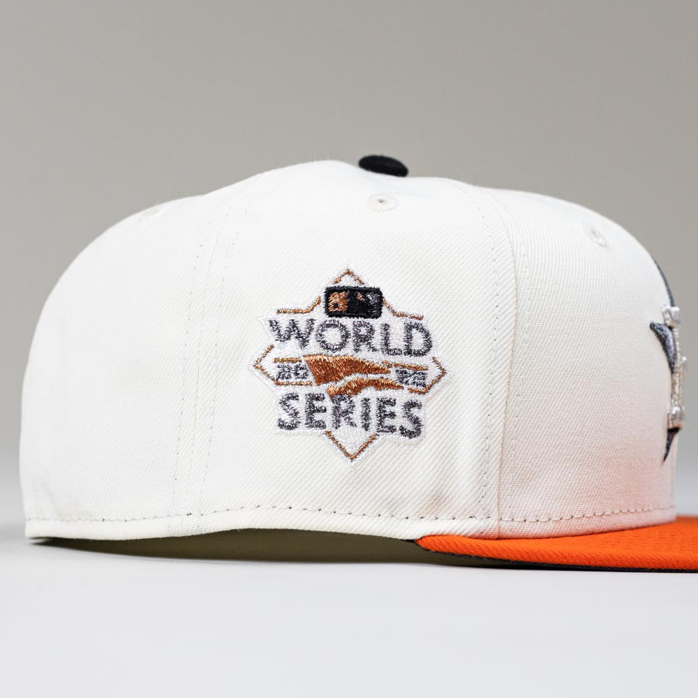 The Orange Soda New Era WS22 Houston Astros 5950 Fitted Hat features a white crown, orange brim, and embroidered World Series logo on the side. The background is plain light gray.