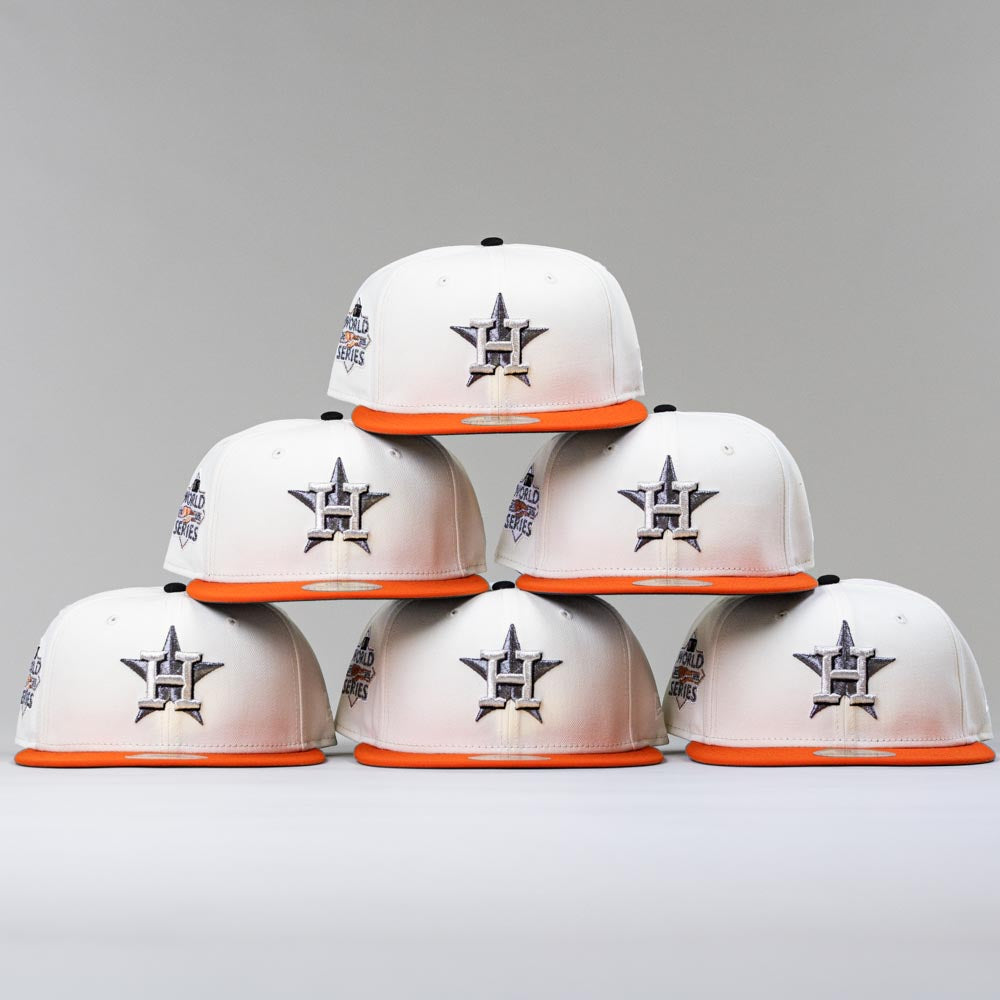 Six Orange Soda New Era WS22 Houston Astros 5950 Fitted hats are stacked in a pyramid against a plain, light gray background.