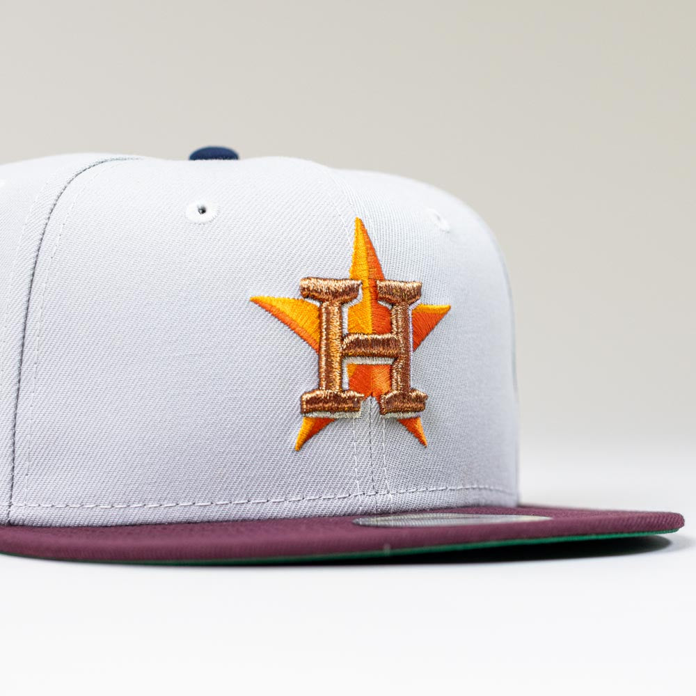 The Shibuya Lights New Era Silver Japan Houston Astros 5950 Fitted Hat features an embroidered gold H over an orange star, a sleek nod to the Astros—complete with a gray crown and maroon brim.