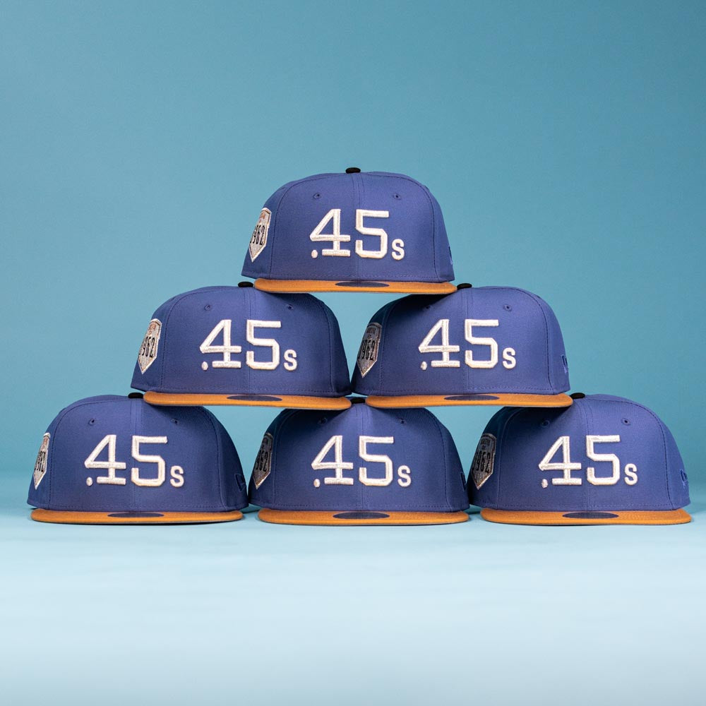 Six Harbor Mark Canvas Houston Astros New Era 5950 Fitted hats with blue crowns and orange brims are stacked in a pyramid against a blue background, each featuring "45s" in white on the front.