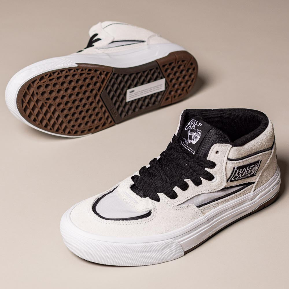 A pair of VN000D9ZYB2 White Black Suede Skate Wafflecup Half Cab Vans Shoes, with one shoe lying on its side to display the Wafflecup sole and the other standing upright on a beige background.