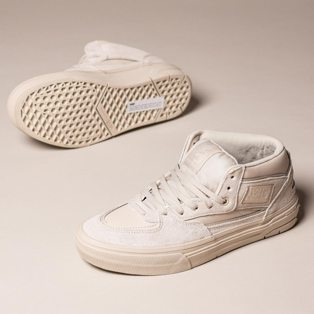 A pair of VN000D9Z2N1 Atiba Oatmeal Suede Skate Wafflecup Half Cab Vans Shoes in beige, one upright showing the side and laces, the other on its side displaying the signature Wafflecup-patterned sole on a neutral background.