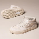 A pair of VN000D9Z2N1 Atiba Oatmeal Suede Skate Wafflecup Half Cab Vans Shoes in beige, one upright showing the side and laces, the other on its side displaying the signature Wafflecup-patterned sole on a neutral background.