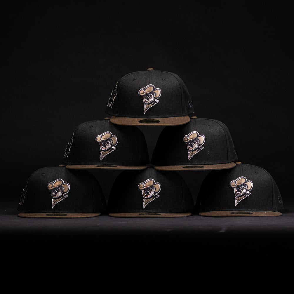 A pyramid stack of six Midnight Cowboy Sugarland Space Cowboys New Era 5950 Fitted hats—black with tan brims and featuring the embroidered Space Cowboys logo—stands out against a dark background.