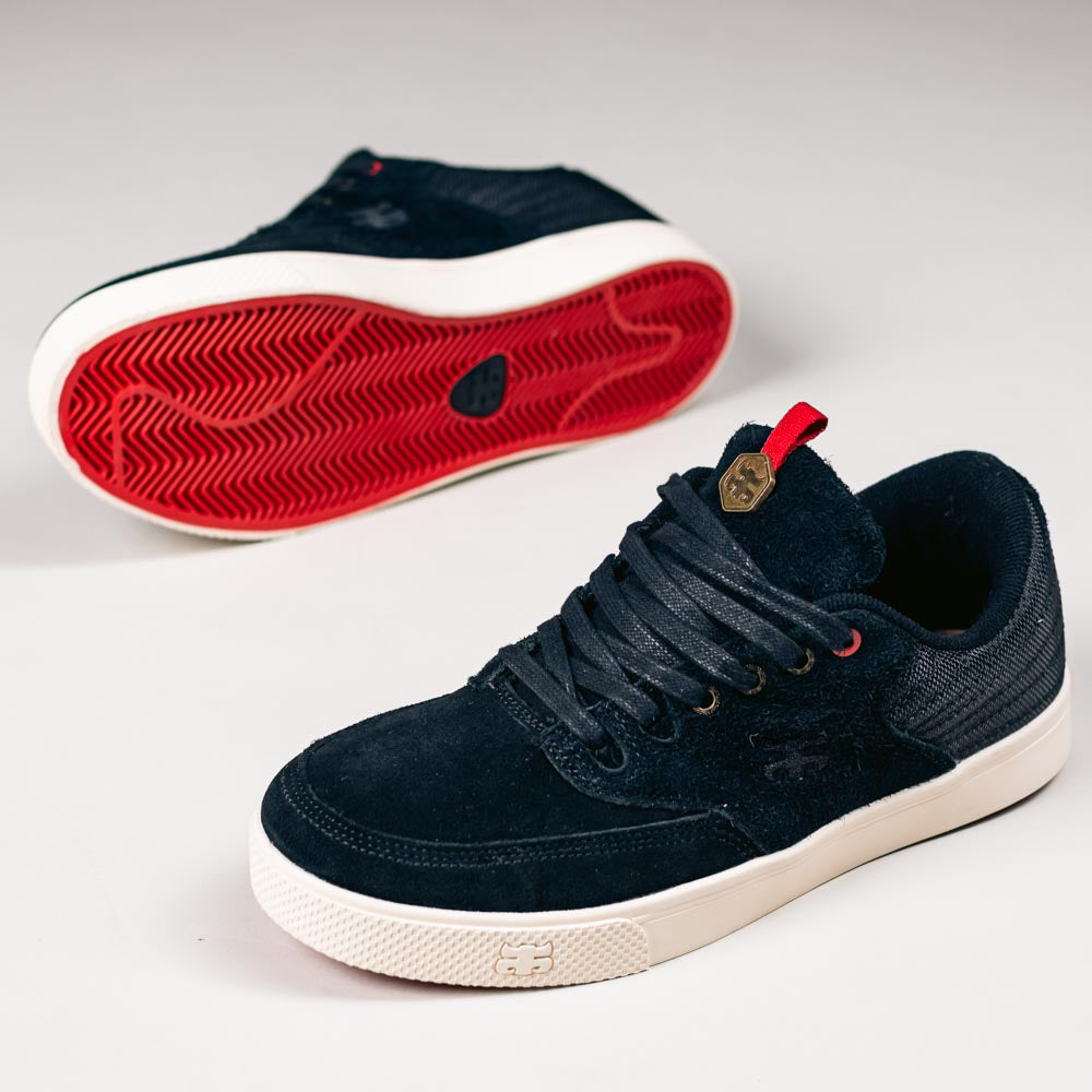 A pair of Poet Black Suede Ballistic Nylon I Path Skateboarding Shoes with white soles and red outsoles is shown, one upright and one on its side, displaying the textured red rubber tread.
