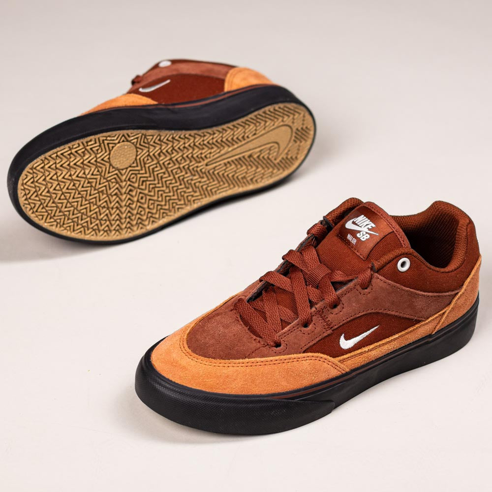 A pair of HF1205200 Cinnamon Light Bone YOUTH Malor GS Nike SB shoes in brown and tan with black soles: one shoe stands upright showing the side and laces, the other lies on its side displaying the durable patterned sole.