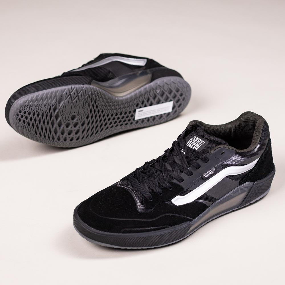 A pair of VN000DA1B5T1 Black Metallic Skate Ave 2.0 Vans Suede Skateboarding Shoes: one upright showing top and side with white stripes, the other flipped to reveal the textured sole—ideal for high-performance skateboarding.