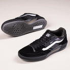 A pair of VN000DA1B5T1 Black Metallic Skate Ave 2.0 Vans Suede Skateboarding Shoes: one upright showing top and side with white stripes, the other flipped to reveal the textured sole—ideal for high-performance skateboarding.