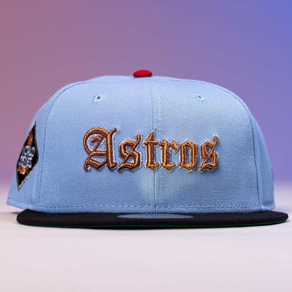 The Sicko Mode Rushmore 2017 B Blue Black Houston Astros New Era 5950 Fitted Hat features a light blue crown, black brim, gold Old English Astros front embroidery, and a left patch on a purple-to-pink gradient background.