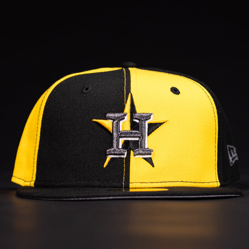 The Hazmat Rushmore Gold Black Pinwheel Houston Astros New Era 5950 Fitted Hat features a black and yellow split design with a silver H and star logo on the front, shown against a dark background.