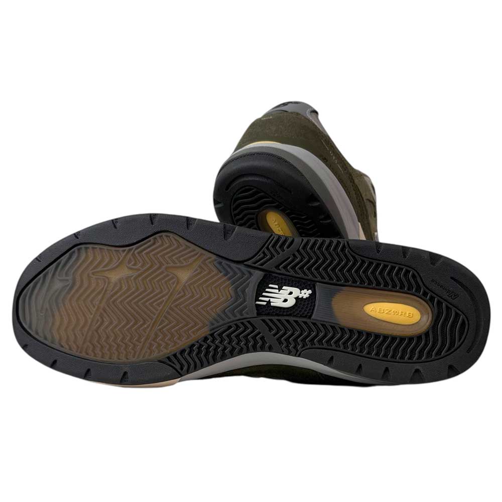 The 933 JKL Andrew Reynolds Grey Day New Balance Numeric Skateboarding Shoes Suede are shown, with one upright and the other revealing the black, textured rubber sole with a New Balance logo and ABZORB cushioning.