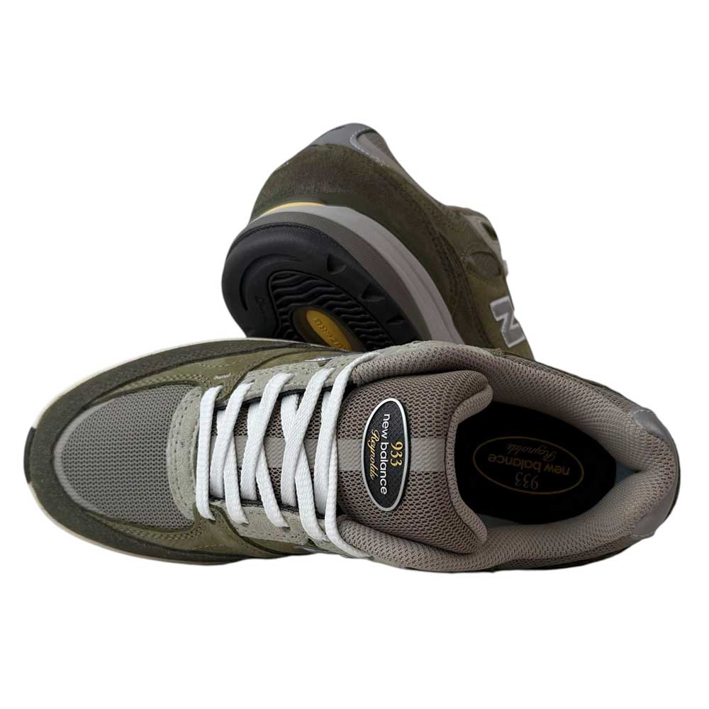 A pair of 933 JKL Andrew Reynolds Grey Day New Balance Numeric Skateboarding Shoes Suede, one upright and one on its side, showcase the sole and logos—merging classic style with durable skateboarding performance.