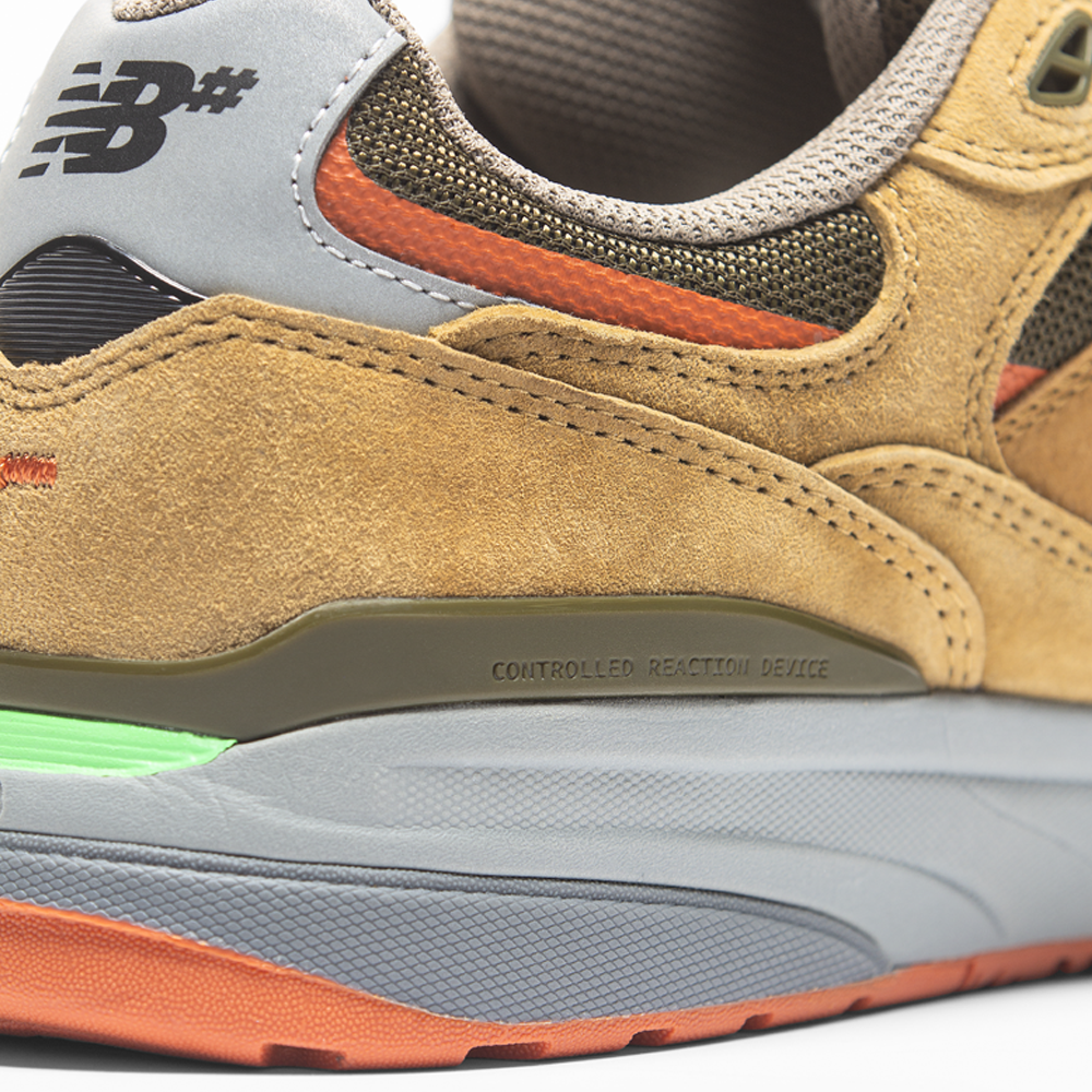 Close-up of the heel of the 933 MNO Andrew Reynolds Brown Grey New Balance Numeric Skateboarding Shoes Suede, featuring suede and mesh in tan, green, and orange with "CONTROLLED REACTION DEVICE" on the midsole.