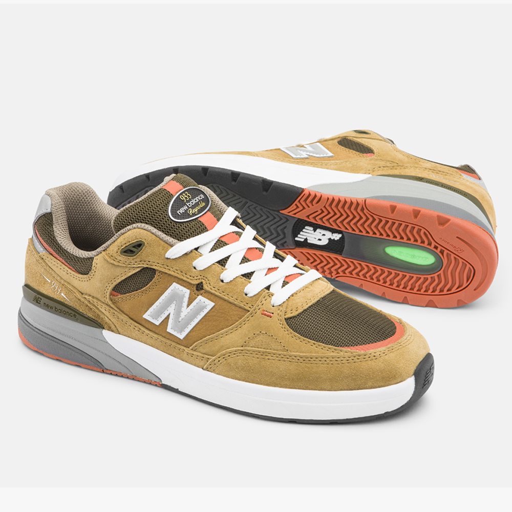 A pair of 933 MNO Andrew Reynolds Brown Grey New Balance Numeric Skateboarding Shoes in suede, featuring white laces, white midsoles, and orange outsole accents. One shoe stands upright; the other shows the sole and side view.