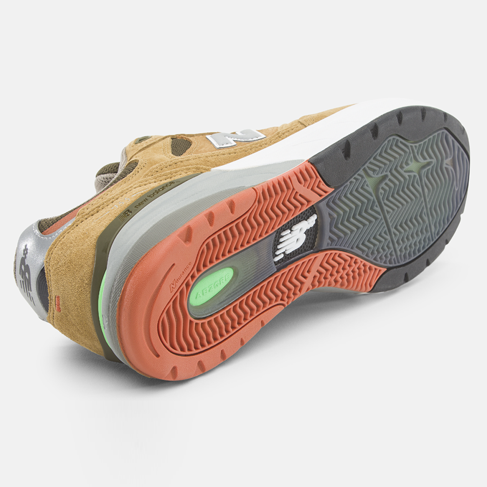 The 933 MNO Andrew Reynolds Brown Grey New Balance Numeric Skateboarding Shoes Suede feature tan and olive suede, a multi-colored outsole with gray, orange, and green, side and bottom views, an NB logo, and are designed for durability in skateboarding.