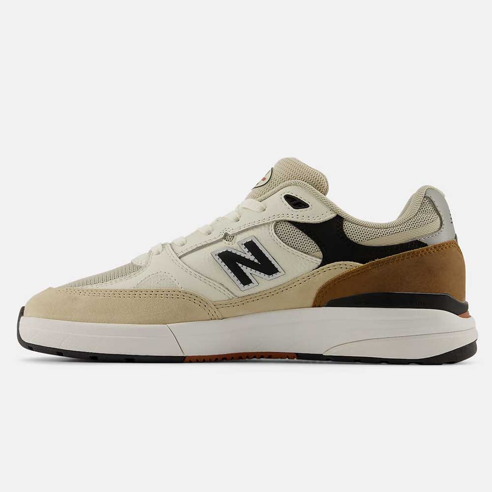 A left side profile of the 933 ONE Quicksand Sea Salt Gray Andrew Reynolds New Balance Numeric Suede Skateboarding Shoe is displayed against a white background, highlighting its heritage-inspired design in cream suede with black, tan, and white accents, and featuring premium cushioning for all-day comfort.