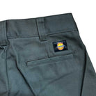 Close-up of olive A865R0OG Spitfire Double Knee Dickies Skateboarding Pant in regular fit twill, showing a back pocket and a rectangular Dickies logo patch with a flaming crown and yellow smiley face above the pocket.