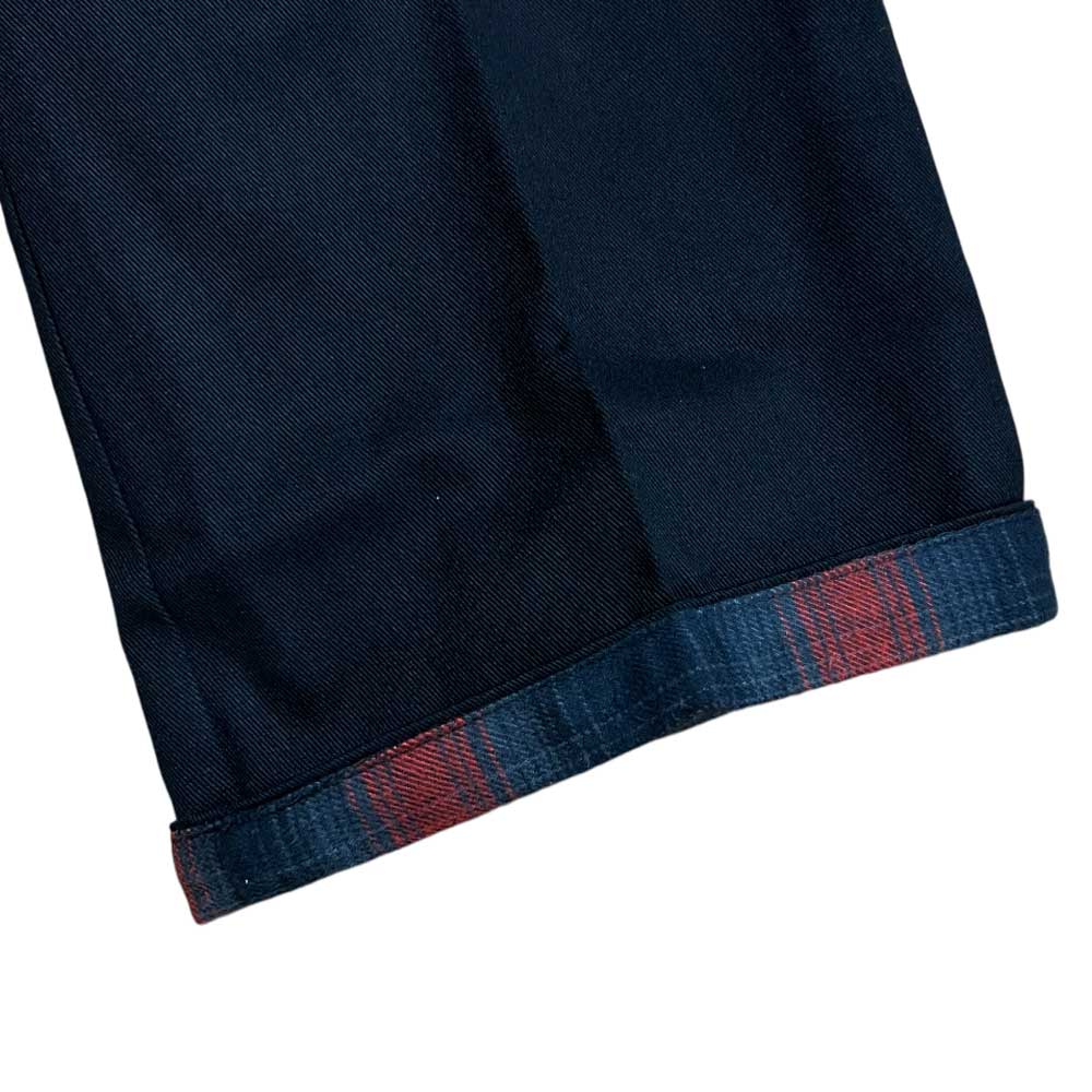 Close-up of the cuff on an A865SBLK Black Spitfire Flannel Cuffed Dickies Skateboarding Pant Regular Fit Twill, showing the folded hem and red and blue Spitfire flannel inner lining.
