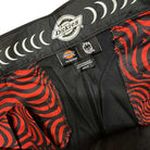 Close-up of the inside waistband of the A865SBLK Black Spitfire Flannel Cuffed Dickies Skateboarding Pant Regular Fit Twill, featuring the Dickies logo, tags, and a red and black swirling Spitfire Flannel lining.
