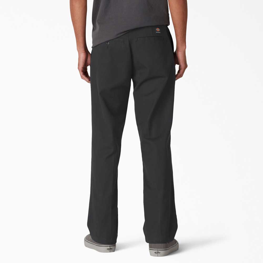 A person wearing A8768 Regular Fit Twill Pant Black Dickies Skateboarding and gray slip-on shoes, shown from the back against a plain white background.