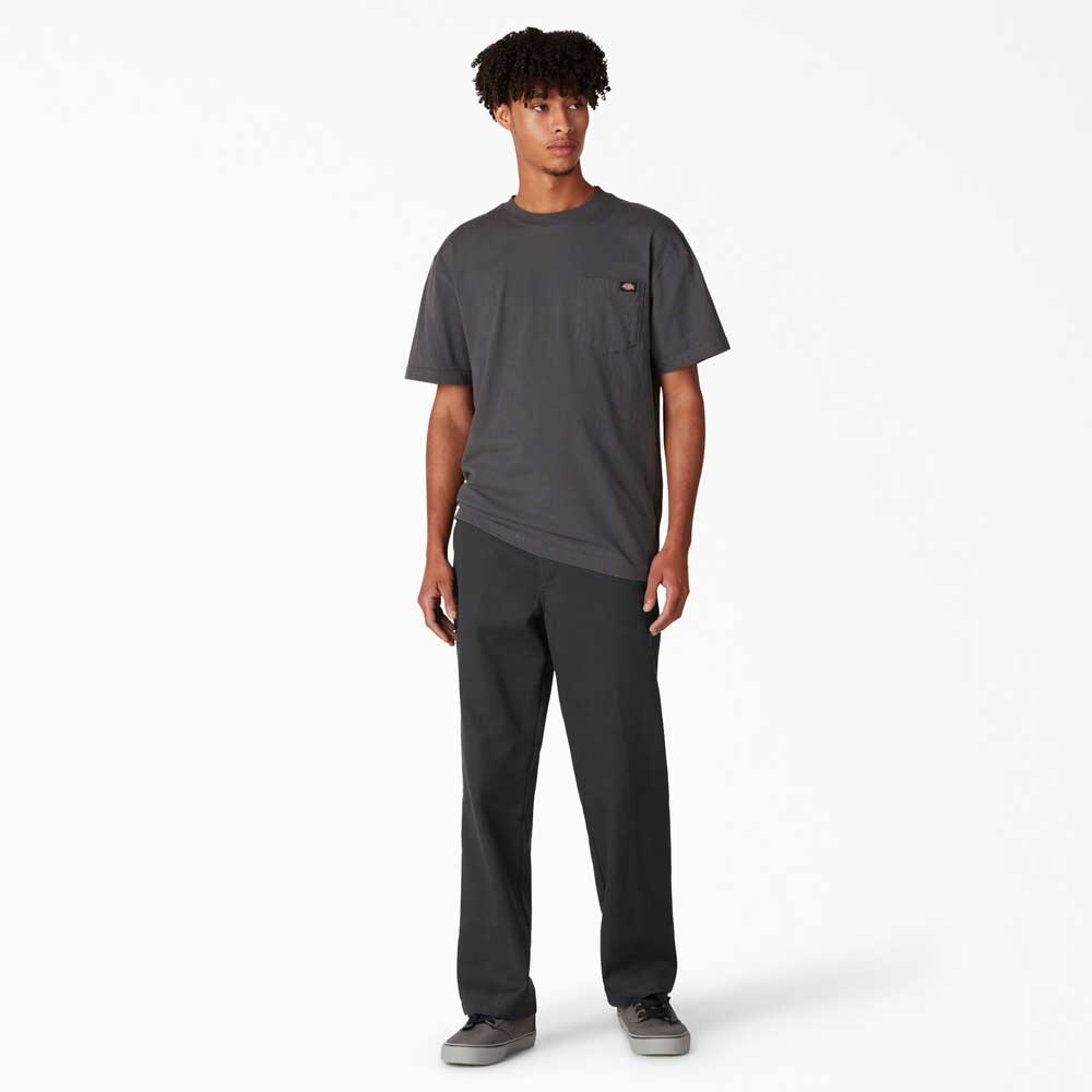 A young man stands facing forward against a white background, wearing a dark gray T-shirt, gray sneakers, and A8768 Regular Fit Twill Pant Black Dickies Skateboarding.