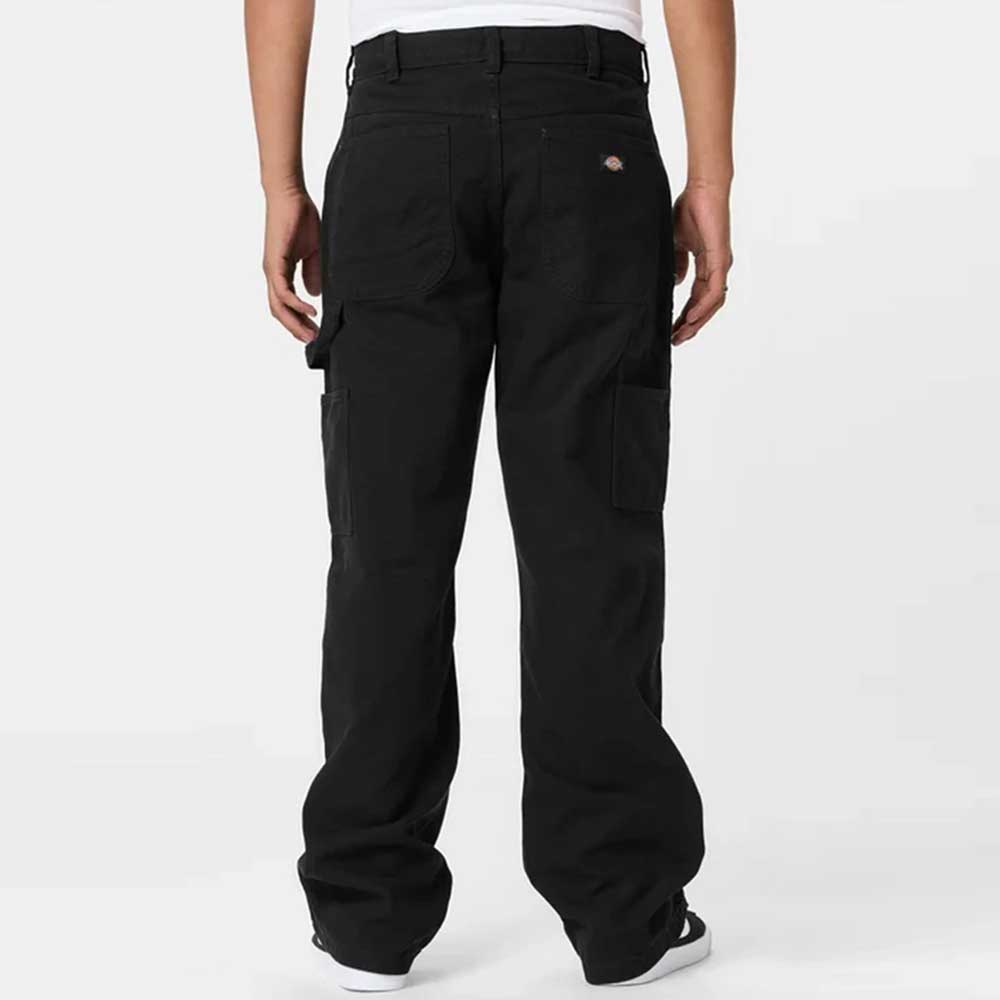 A person is shown from the back wearing A87PE Black Double Knee Canvas Carpenter Pant Dickies Skateboarding, featuring a baggy fit, large side pockets, and a logo patch above the right back pocket, paired with a white t-shirt against a light background.