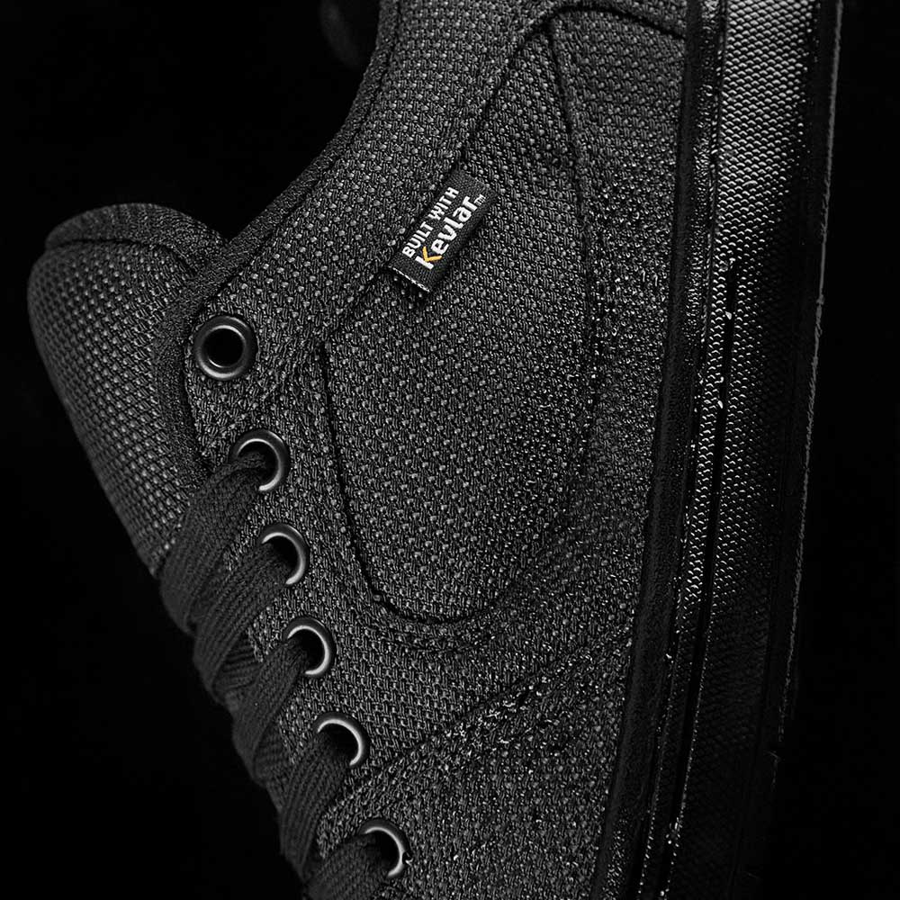 Close-up of the Accel Kevlar Black Es Shoes, a black canvas skate shoe with matching laces and eyelets, plus a woven Rewar label—ideal for skateboarding style inspired by the classic éS Accel, shown against a black background.