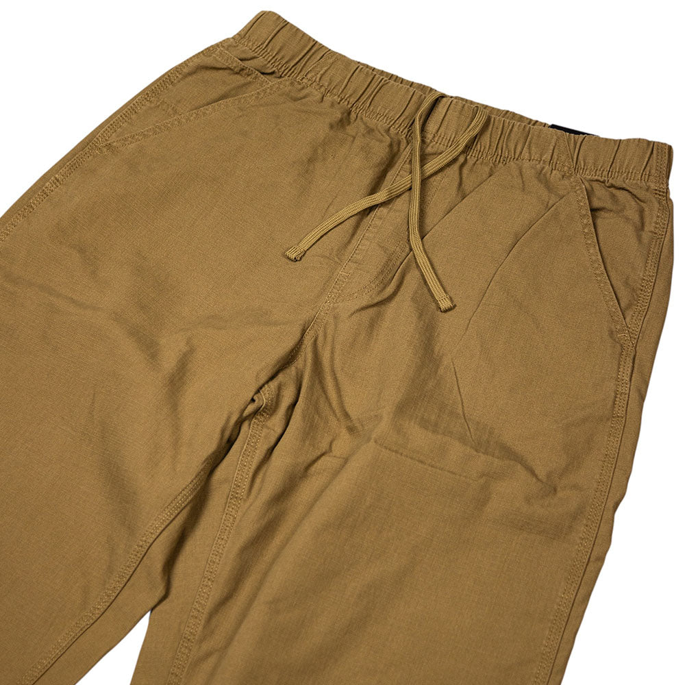 The Vans Addison Barrel Olive Brown VN0010HYOVB Pants, featuring an elastic waistband with a drawstring and side pockets, are designed in a loose-fit denim style reminiscent of skate jeans and are displayed laid flat on a white background.