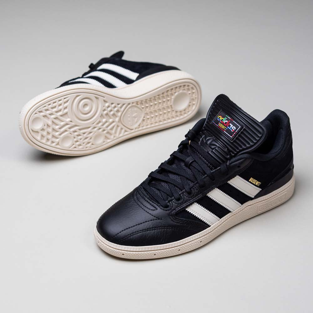 A pair of Busenitz Black White HQ4708 Adidas Skateboarding Suede Shoes are shown on a light gray surface—one upright, displaying its side and top, the other on its side to show the suede sole and signature white stripes.