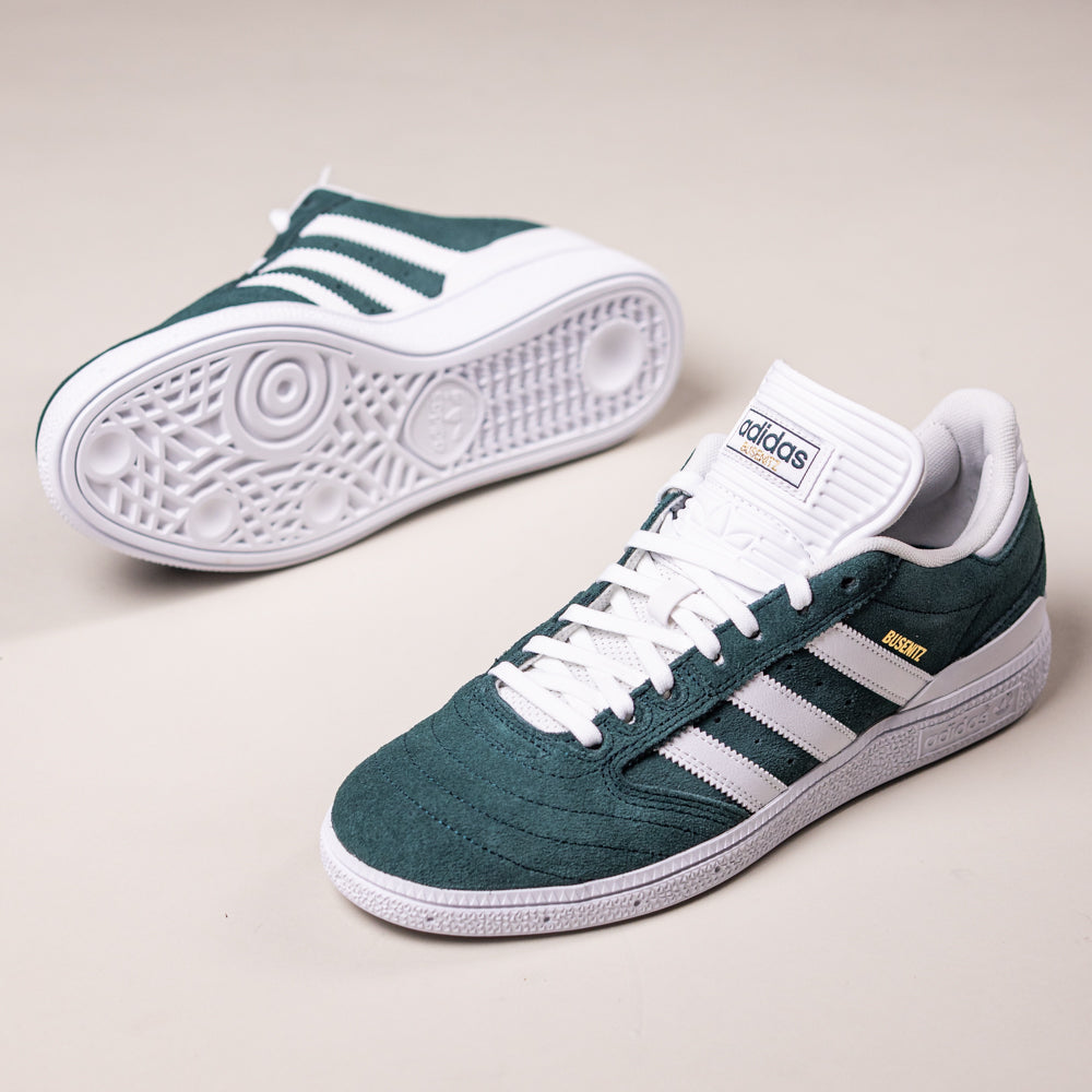 The Busenitz HQ7534 Green White Adidas Skateboarding Suede Shoes feature durable green suede uppers, white stripes, and a sturdy sole—one upright and one on its side to show the design—making them ideal for skateboarding.