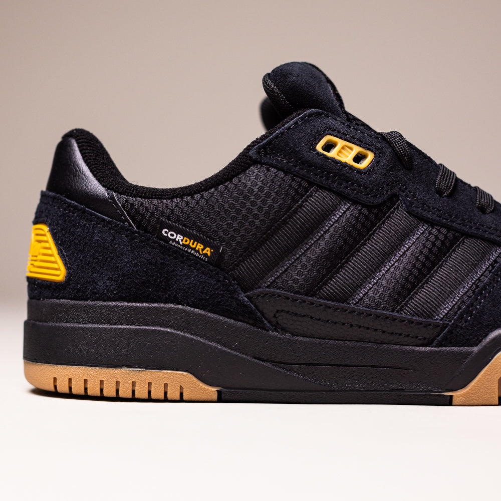 The KJ5054 Cordura Carbon Black Tekkira Cup Adidas Skateboarding shoe has a suede upper with mesh details, yellow heel and eyelet accents, signature black stripes, gum rubber sole, and durable CORDURA branding near the heel.