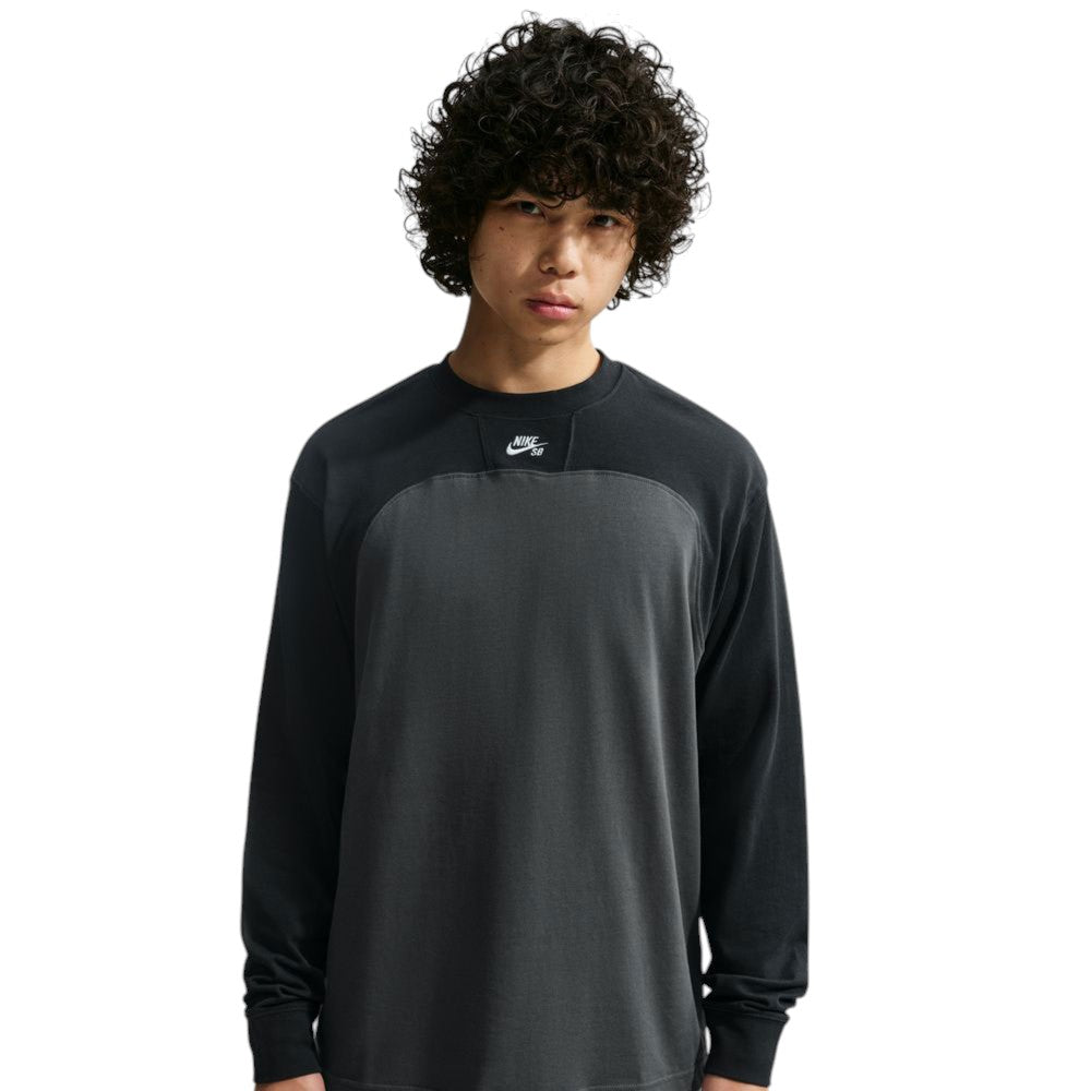 A person wears the Airmail Longsleeve IM5430060 Black Gray Skate Longsleeve T-Shirt, a durable, midweight cotton long-sleeve crewneck in black and gray featuring a small logo patch at the center of the neckline.