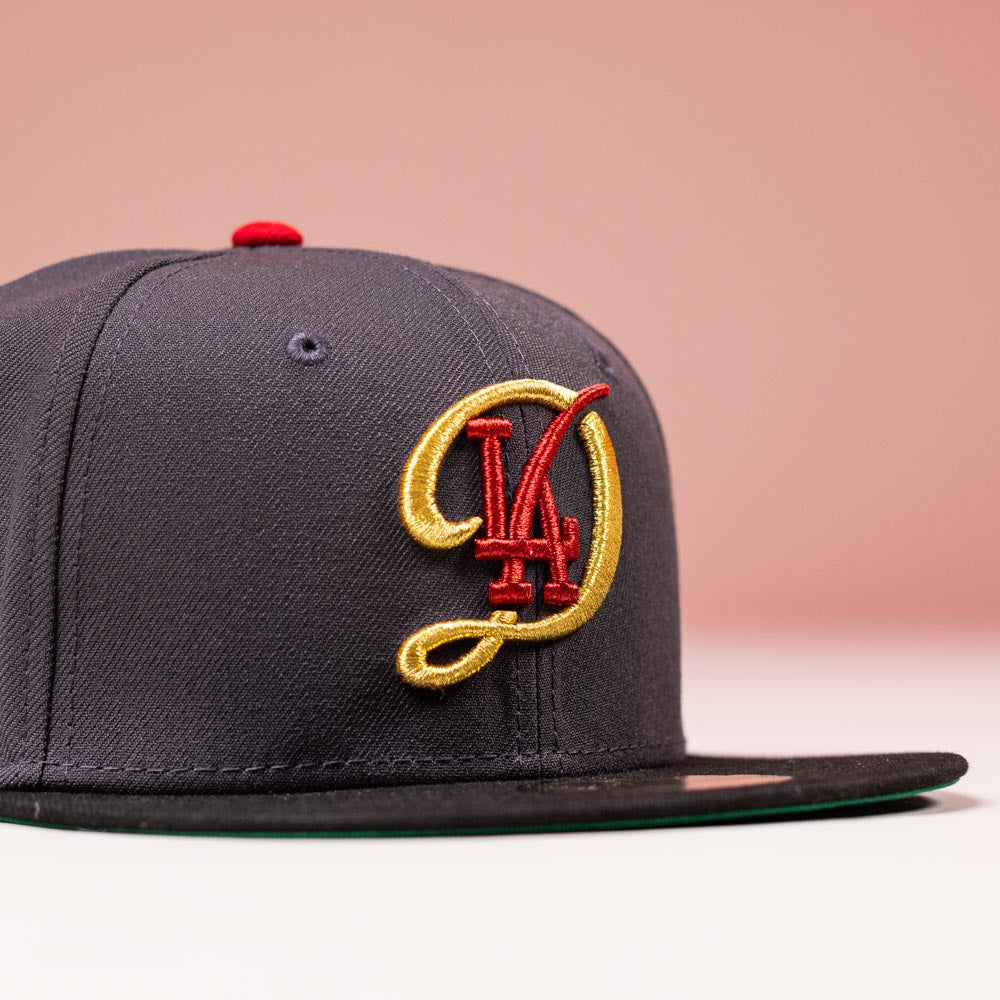 The Bones Pack Los Angeles Dodgers New Era 5950 Fitted Hat features a dark color, flat brim, and large red and gold “LA” embroidery on the front—ideal for fans wanting a stylish, fitted look.