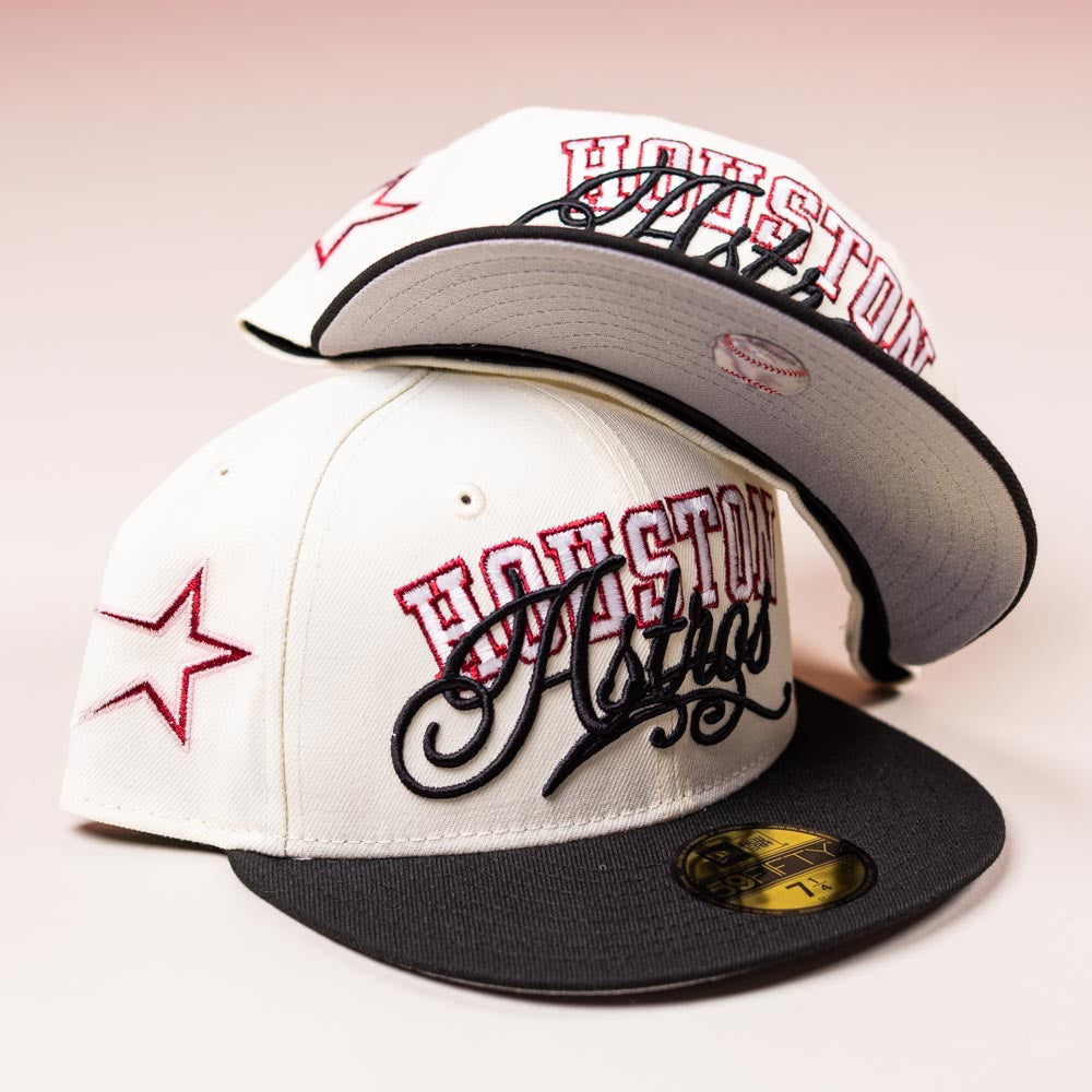 Two D BOY Houston Astros New Era 5950 fitted hats in ivory, black, and red are shown: one upright and the other upside down to display the brim's underside. Both feature red star designs on the side.