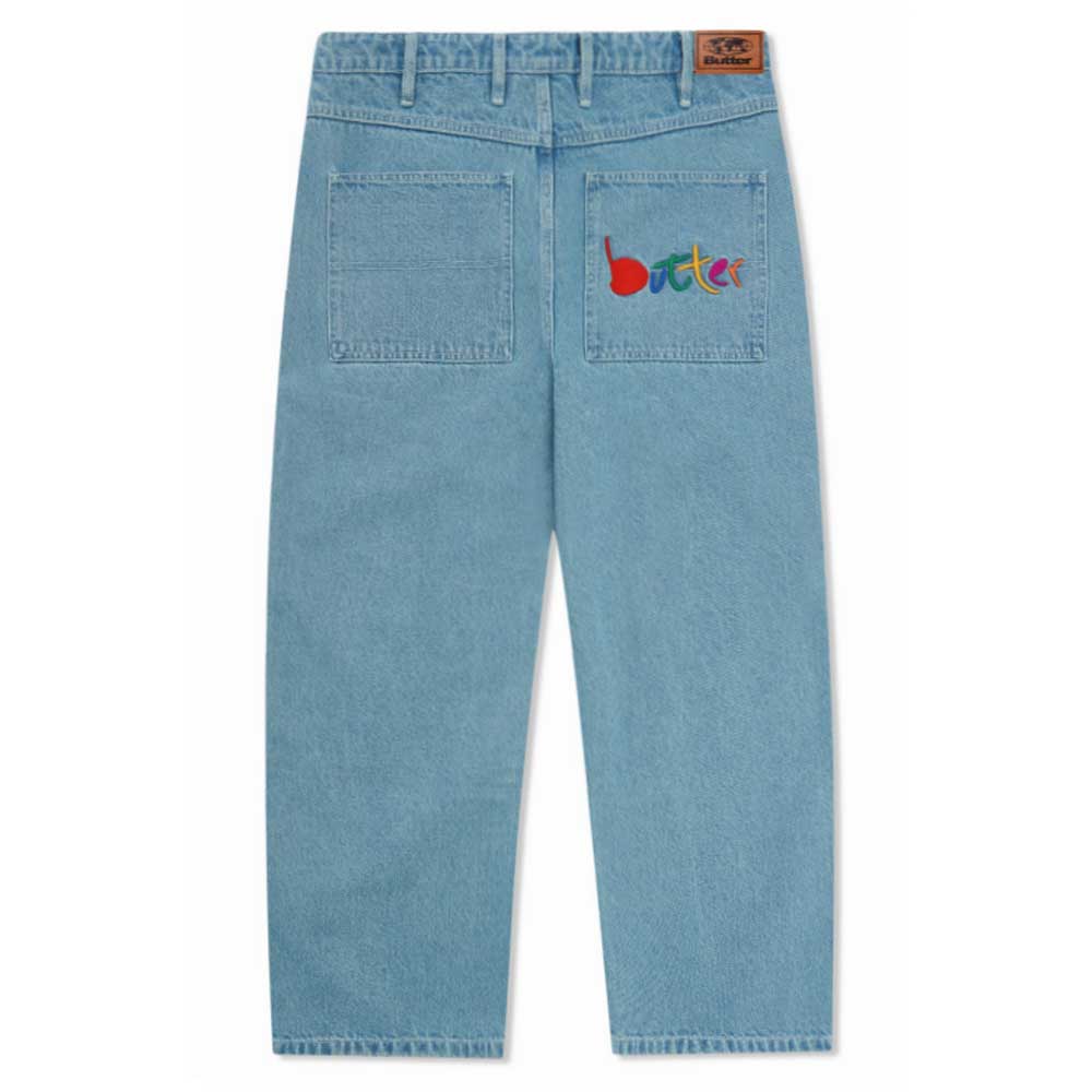 Art Mid Blue Denim Jeans Butter Goods, shown from the back with two rear pockets. The right pocket features a colorful Butter Goods logo, while a brown branded patch accents the waistband.