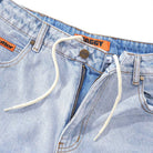 Baggy Light Blue Denim Jeans by Butter Goods feature a white drawstring, visible button, partially open zipper, orange BAGGY and 32 tags at the waistband, and an orange label near the pocket. Made from 100% cotton denim.