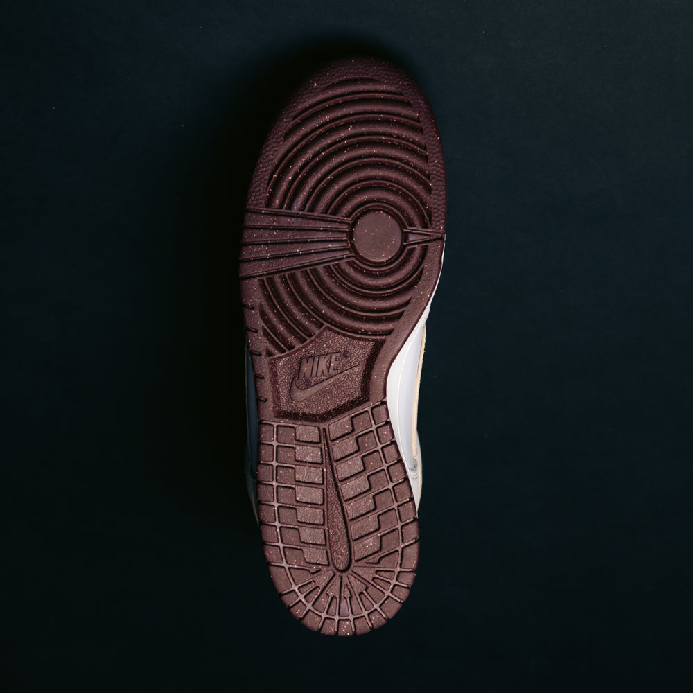 The image displays the bottom view of a single Ivory Sand Blue Void Dunk High Pro x Beyond IU4491100 Nike SB Skateboarding Shoe, highlighting its dark brown sole with a circular tread pattern and Nike logo, set against a solid black background.
