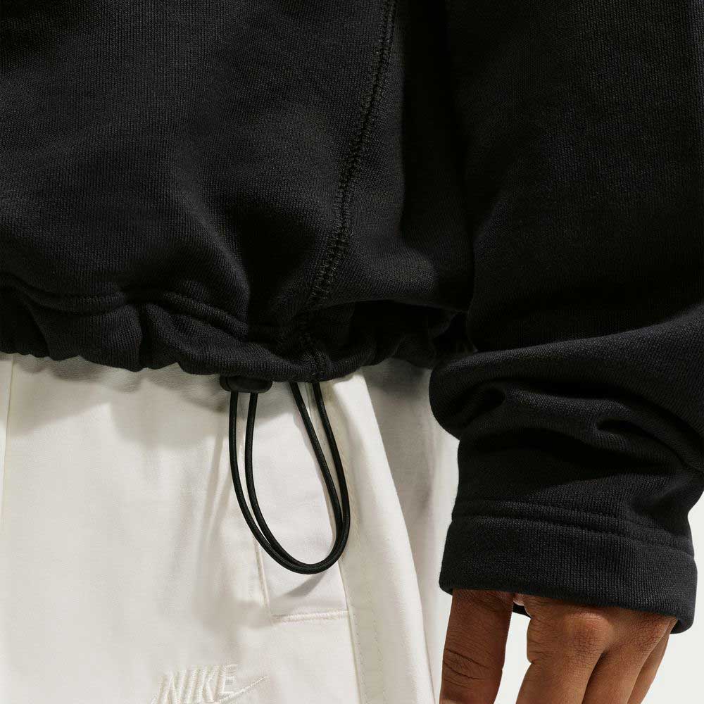 A close-up shows someone wearing a Black IM5463010 Skate 1/2 Zip Fleece Crew from Nike SB Skateboarding and white Nike sweatpants. Only part of the torso and one hand are visible; both items are machine washable.