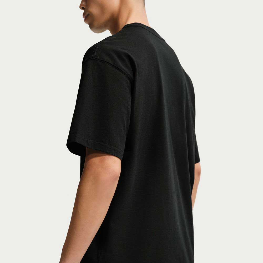 A person is shown from the back and side wearing the Black SF Muni Bus Pass Tee IU1265010 T-Shirt Nike SB Skateboarding Tee against a light gray background, with their head slightly turned to the left, partially revealing their face.
