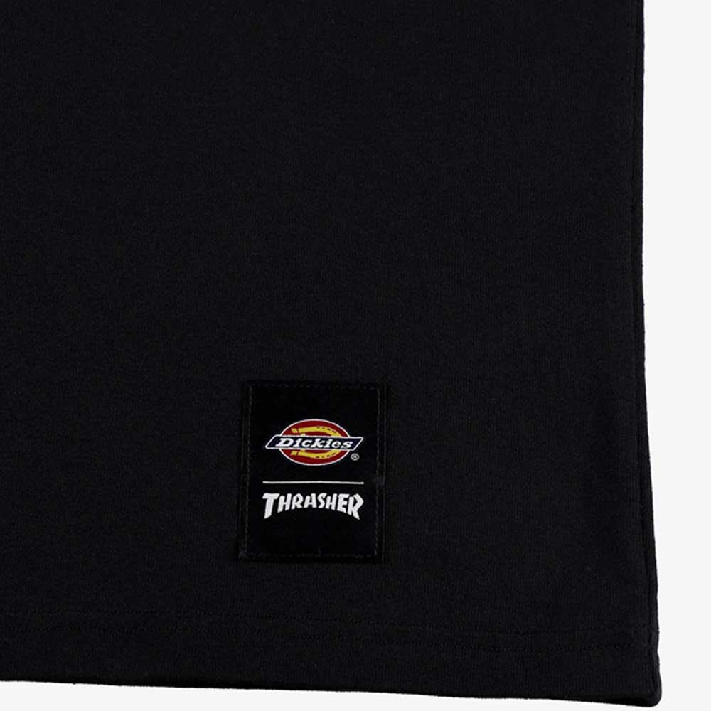 Close-up of the Black Tee Thrasher Magazine x Dickies Skateboarding A88IU BLK, made from 100% cotton, with a rectangular logo patch near the hem, shown against a white background.