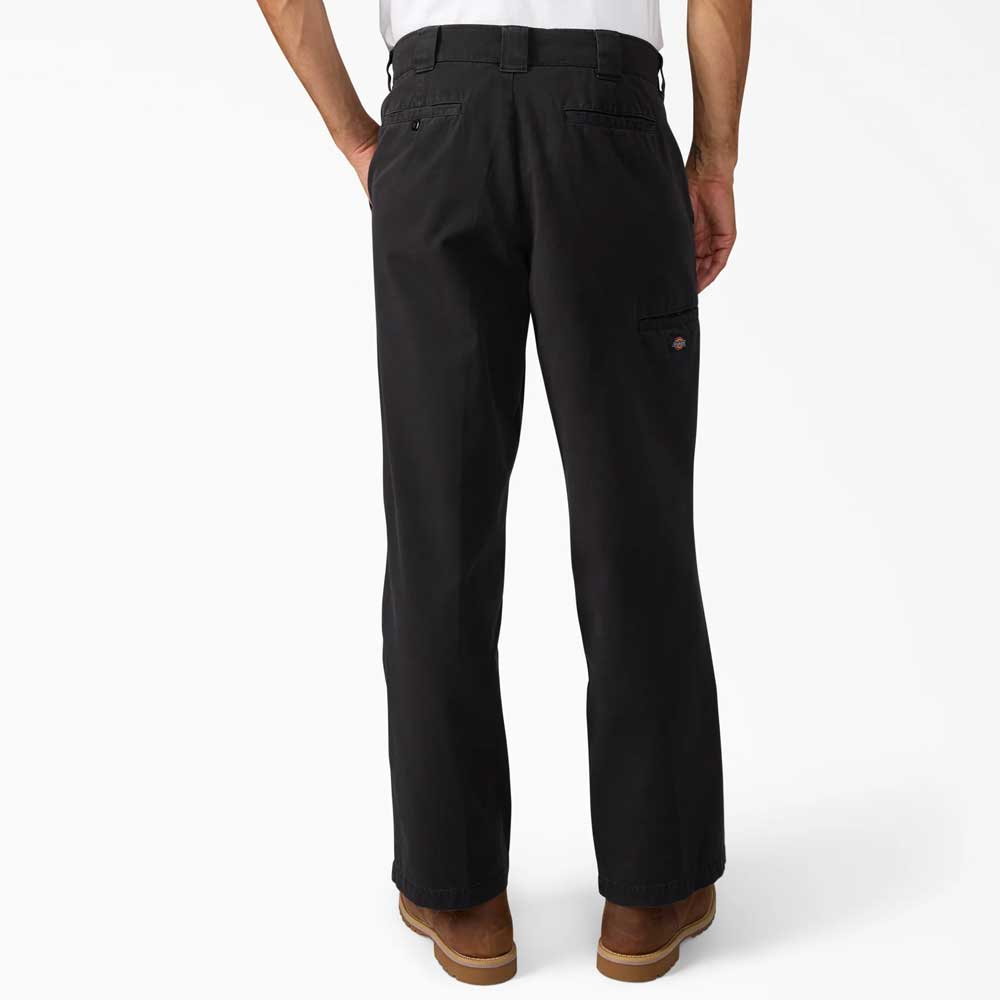 A person is shown from the back wearing Dickies Skateboarding Black Worn In Double Knee Pant A89TCBLK, 100% cotton, loose fit, straight-leg pants with back pockets and a logo patch, paired with brown shoes against a white background.