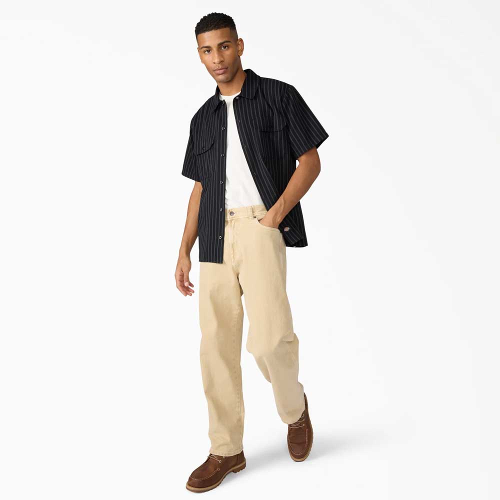 A man stands facing forward against a white background wearing the Black Worn In Lightweight Work Shirt A89G7BLK Dickies Skateboarding, beige pants, and brown shoes.
