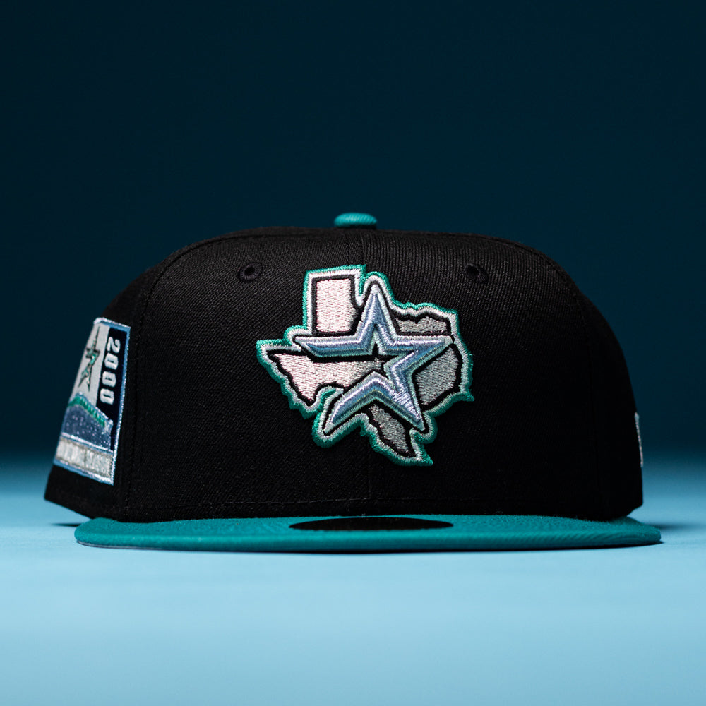The Silver Lining Black Teal 2000 Houston Astros New Era Hat 5950 Fitted features a black crown with a teal brim, an embroidered Texas outline and star on the front in Chrome Black style, a “2000” patch on the left side, and an extra Houston Astros-inspired star detail.